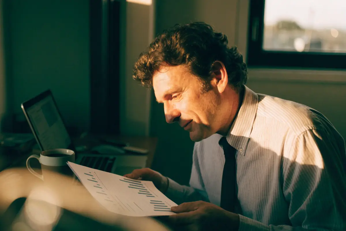 A business owner reviewing a monthly results report with a cup of coffee