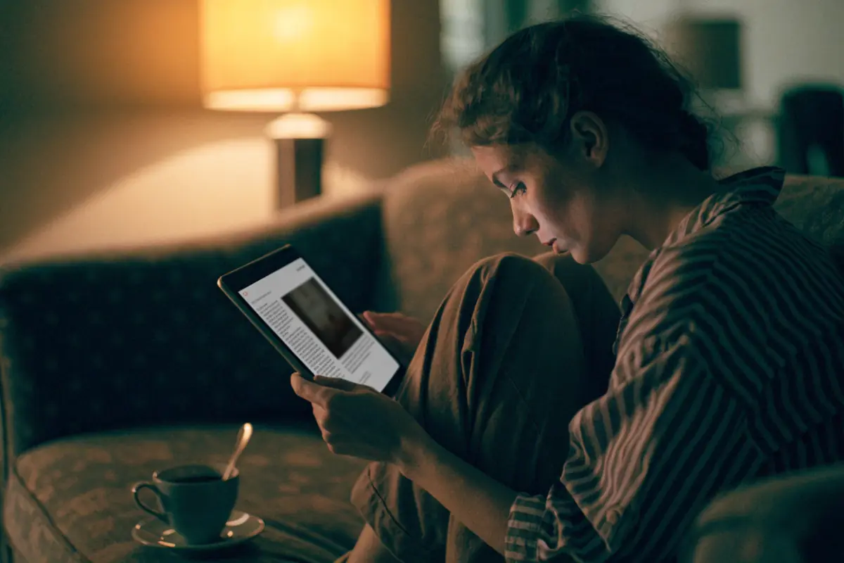 A woman reading on a tablet on her couch as an ad appears beside the article
