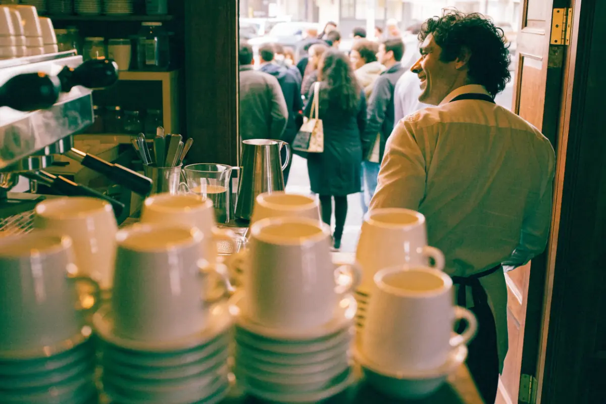 A shop owner counting a busy line of customers at the register