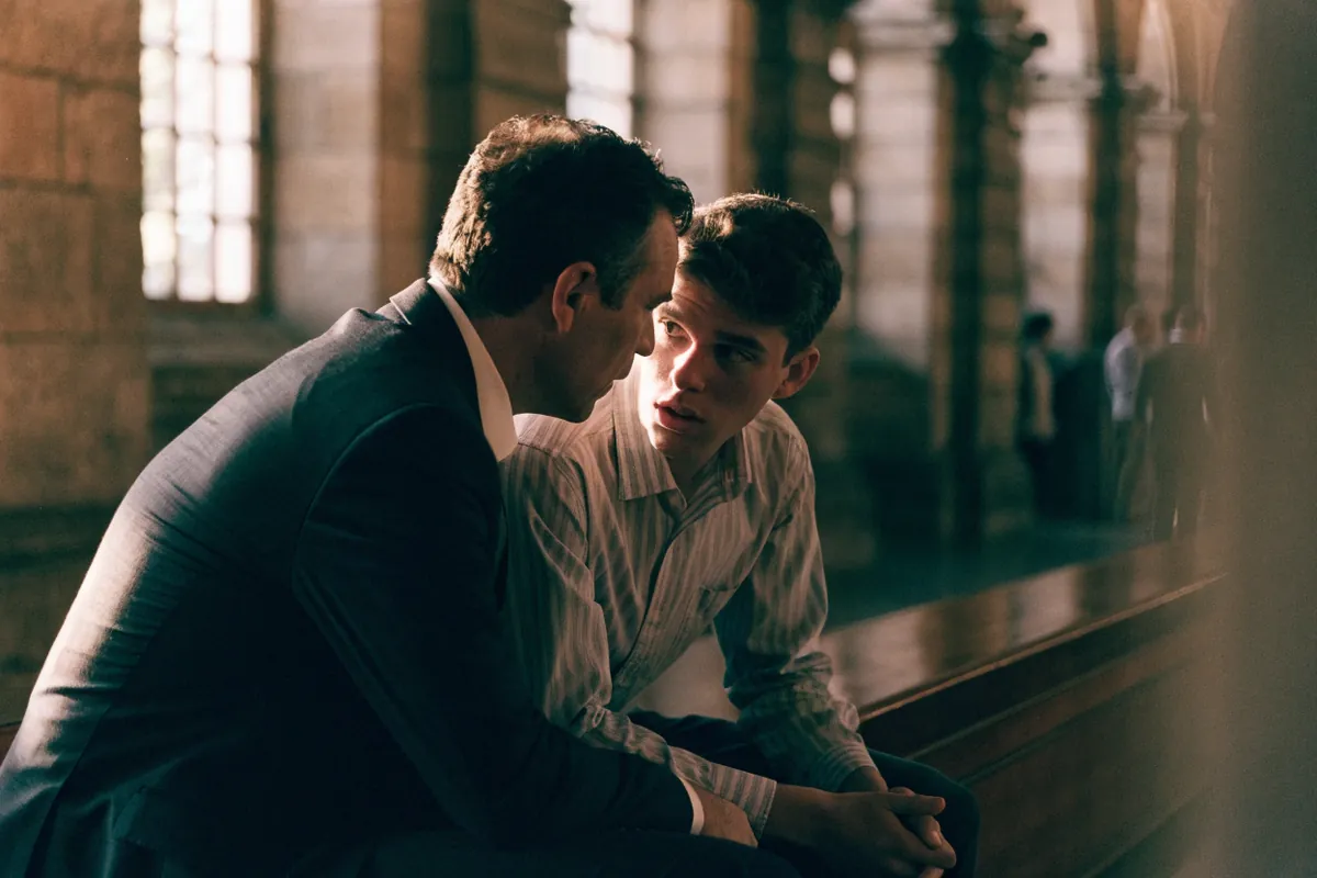 A defense attorney talking quietly with a worried young client on a courthouse bench