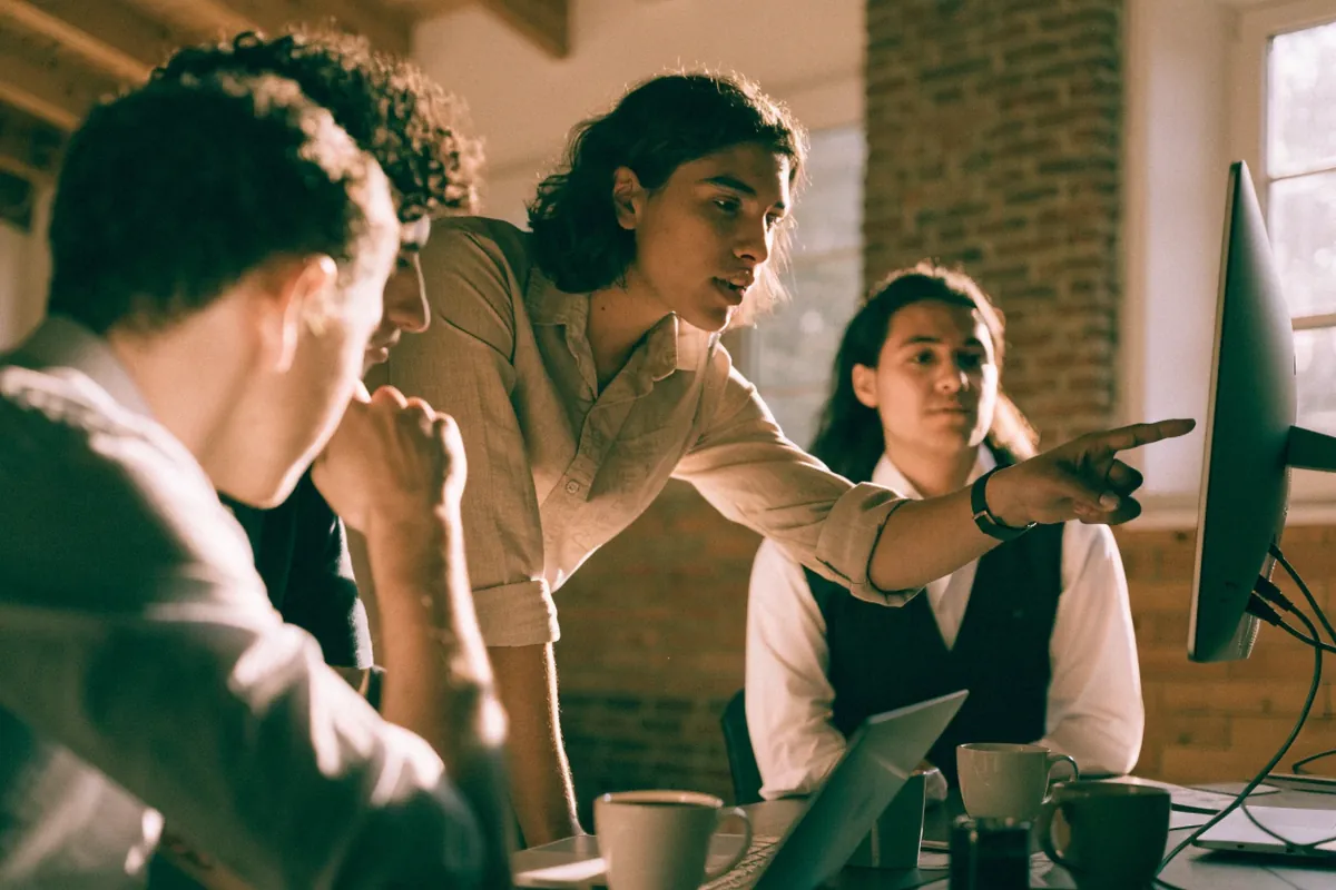 A small software team gathered around a monitor during a product demo