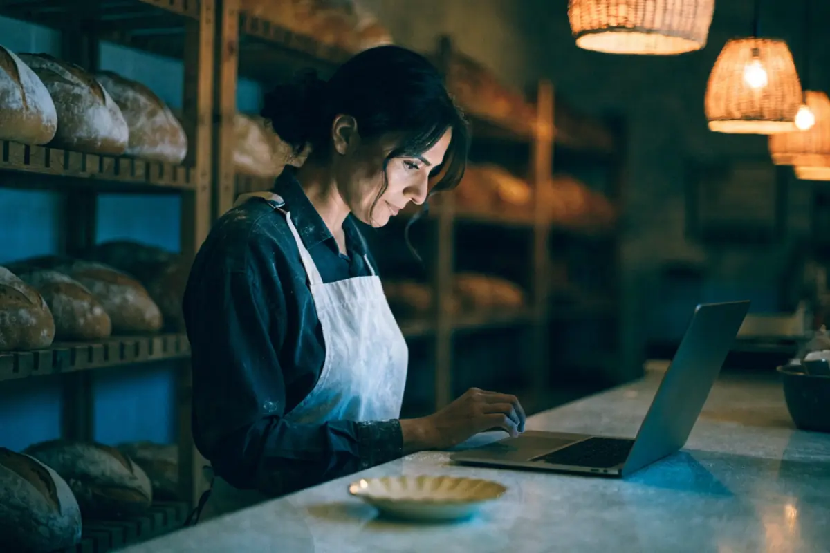 A bakery owner proudly viewing her new website on a laptop