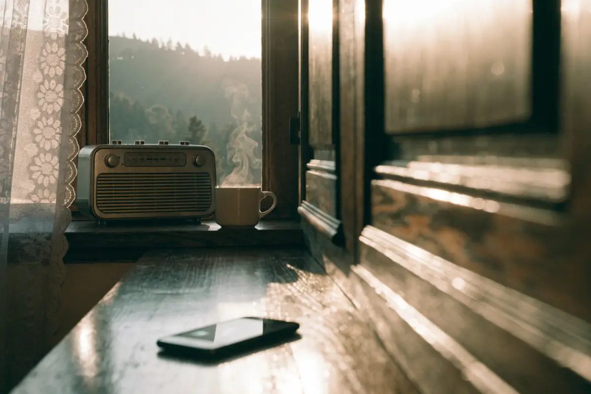 A radio on a sunlit kitchen windowsill and a phone lighting up on the counter